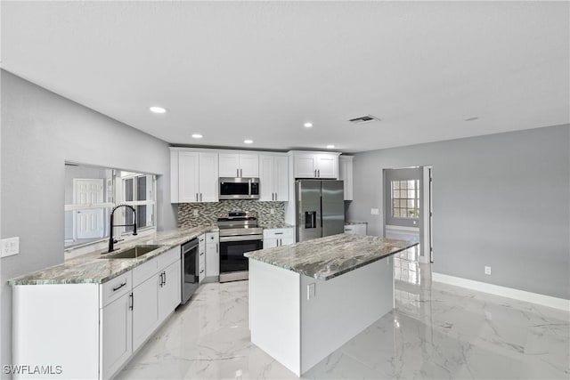 kitchen with a kitchen island, backsplash, marble finish floor, stainless steel appliances, and a sink