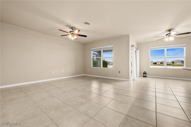 tiled empty room with ceiling fan and plenty of natural light