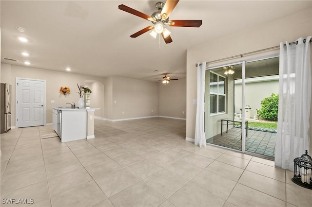 unfurnished living room featuring ceiling fan, light tile patterned floors, and sink