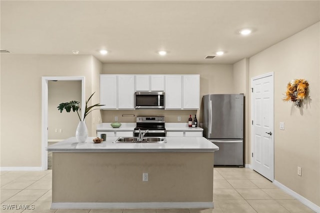 kitchen with light tile patterned floors, stainless steel appliances, and a kitchen island with sink