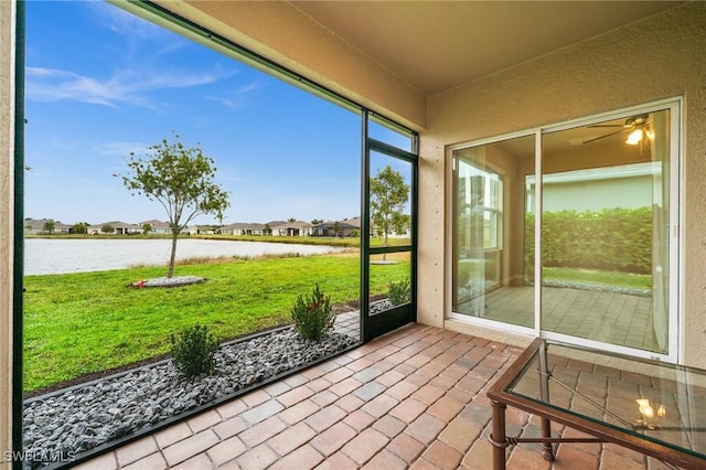 unfurnished sunroom featuring ceiling fan and a water view