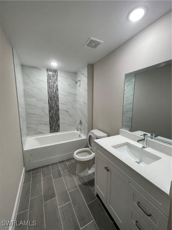 full bathroom with tiled shower / bath combo, vanity, and toilet