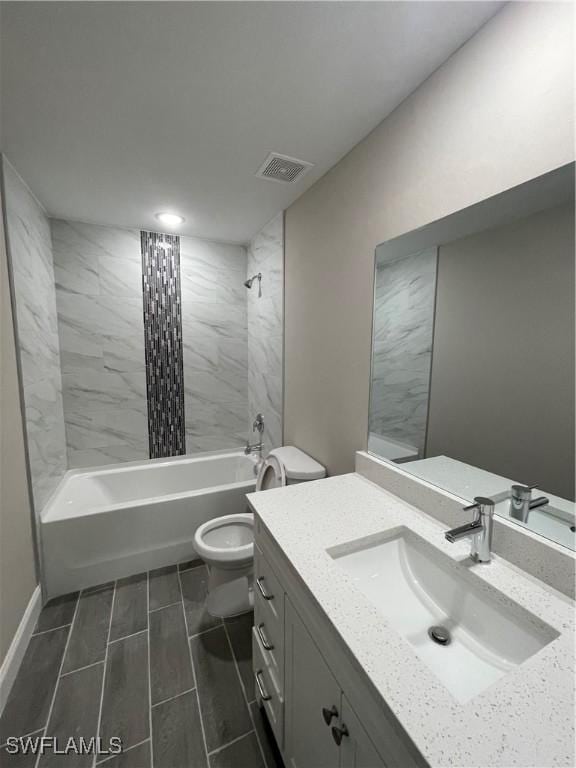 full bathroom with tiled shower / bath, vanity, and toilet