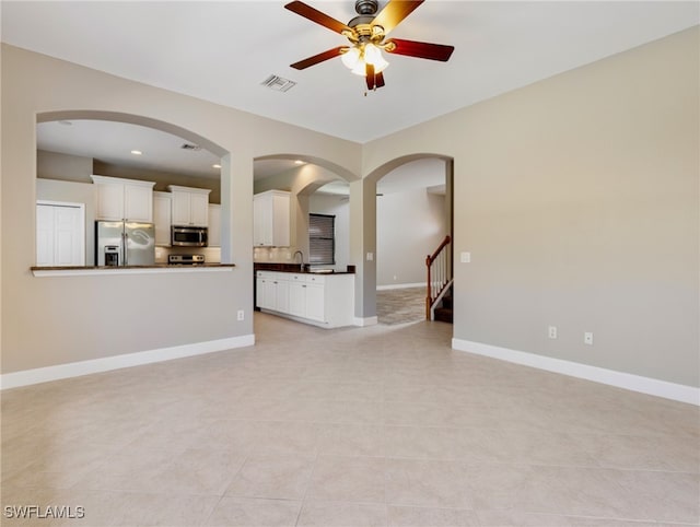 unfurnished living room with sink, light tile patterned floors, and ceiling fan