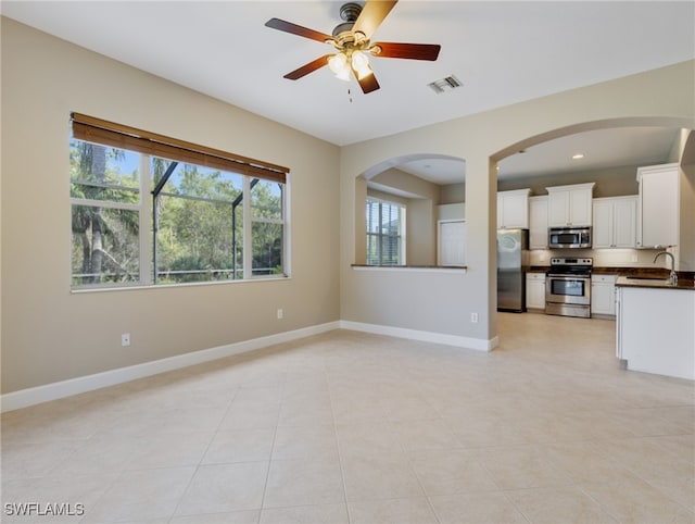 unfurnished living room with light tile patterned floors, sink, and ceiling fan