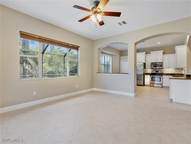 unfurnished living room featuring ceiling fan, light tile patterned floors, and sink