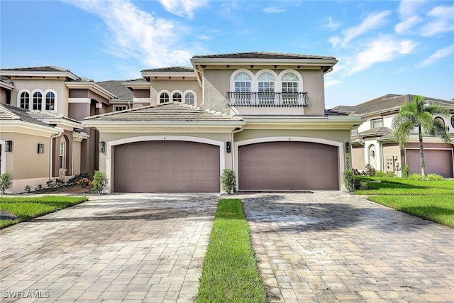 mediterranean / spanish home featuring stucco siding, decorative driveway, a balcony, and a tile roof