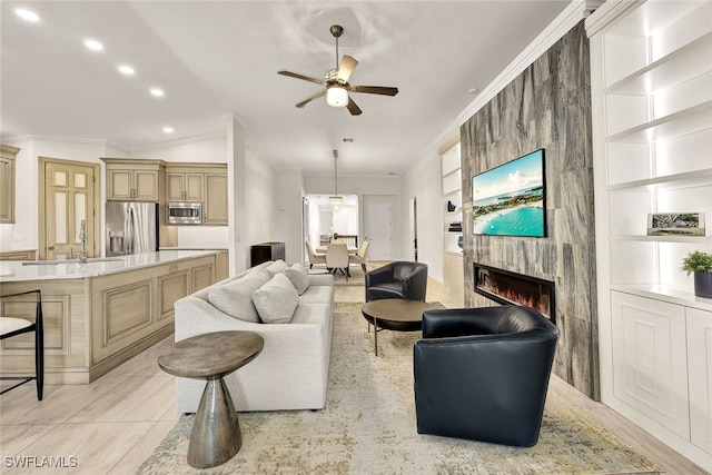 living area featuring built in shelves, crown molding, recessed lighting, a fireplace, and a ceiling fan