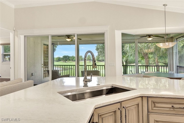 kitchen with a ceiling fan, a sink, decorative light fixtures, crown molding, and lofted ceiling