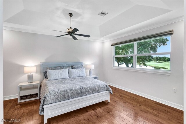 bedroom featuring a raised ceiling, ceiling fan, dark wood-type flooring, and ornamental molding