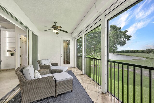 sunroom / solarium with a ceiling fan and a water view