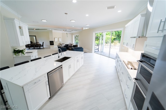 kitchen with appliances with stainless steel finishes, white cabinets, sink, and an island with sink