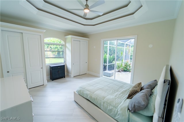 bedroom featuring multiple windows, a tray ceiling, crown molding, and ceiling fan