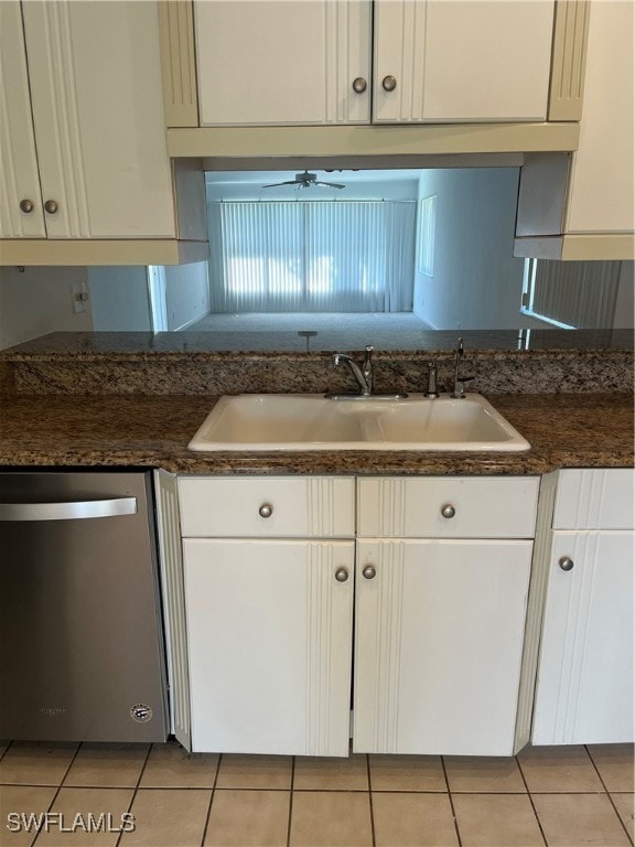 kitchen featuring sink, dark stone counters, stainless steel dishwasher, and light tile patterned floors