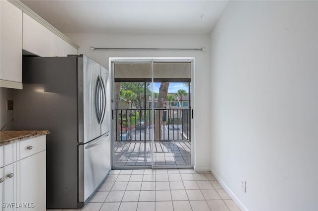 4130 Looking Glass Ln Unit 3802, Naples, FL 34112 - kitchen featuring freestanding refrigerator, white cabinetry, light tile patterned floors, and dark stone countertops