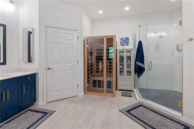 bathroom with wood-type flooring, a shower with shower door, and vanity