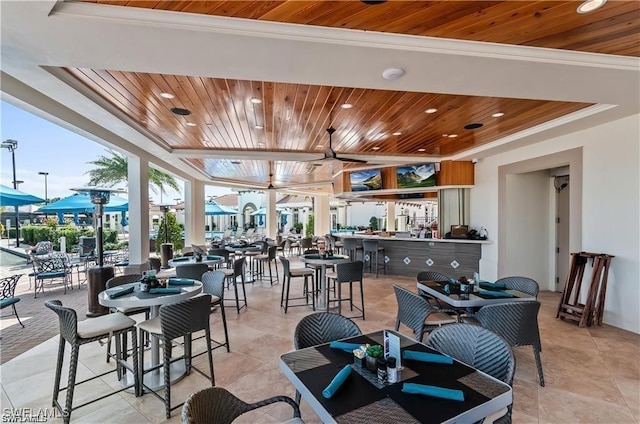 dining space featuring crown molding, wooden ceiling, expansive windows, and ceiling fan