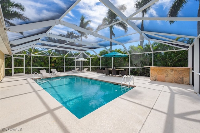 view of pool with glass enclosure and a patio