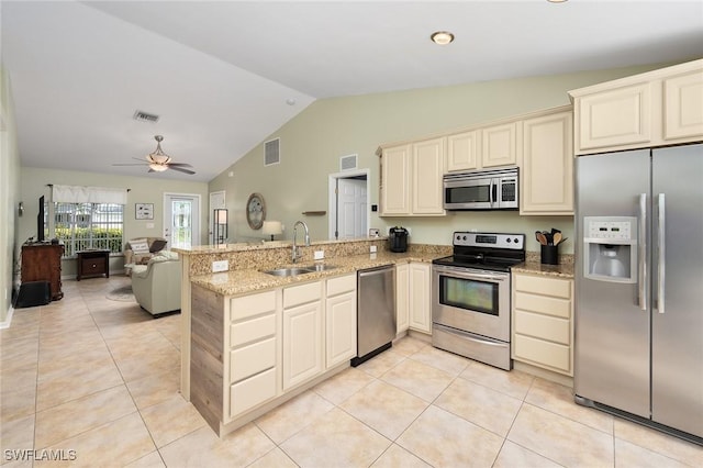 kitchen with light stone counters, appliances with stainless steel finishes, kitchen peninsula, and sink