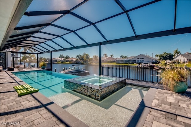 view of pool featuring a water view, glass enclosure, a pool with connected hot tub, and a patio