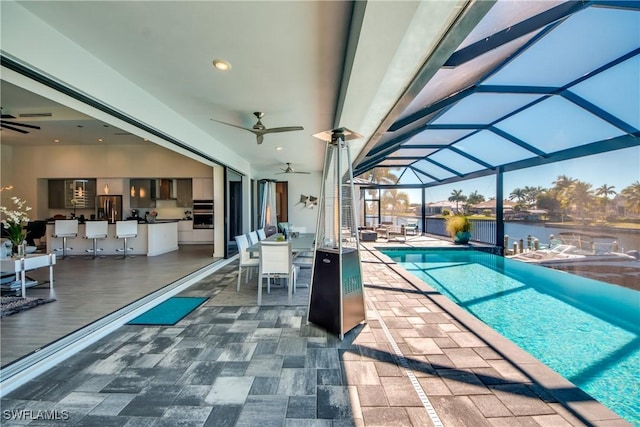 pool featuring a lanai, a water view, ceiling fan, and a patio