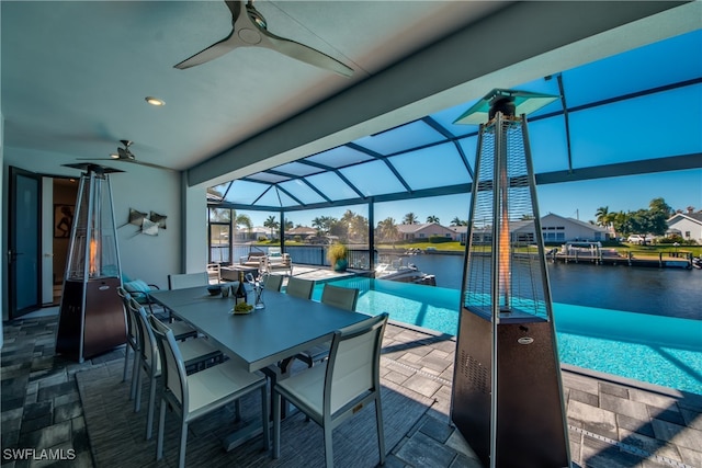 view of patio / terrace featuring a lanai, ceiling fan, and a water view