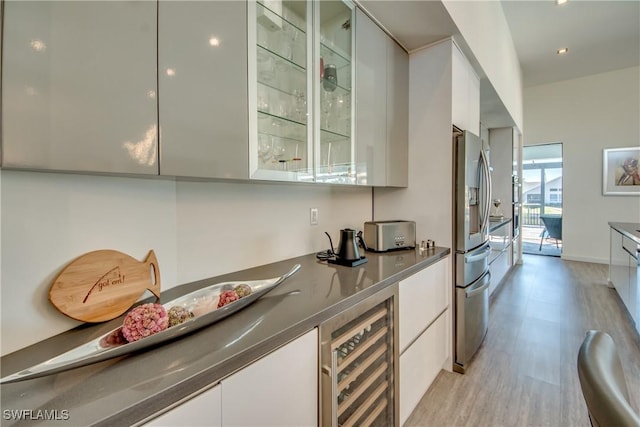 interior space with light wood-style floors, beverage cooler, stainless steel fridge, and baseboards