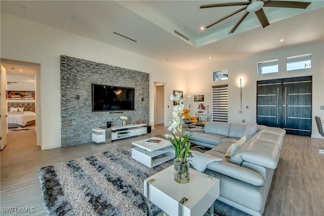 living area featuring light wood-style flooring, visible vents, and ceiling fan