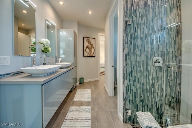 full bathroom featuring double vanity, a stall shower, baseboards, and a sink