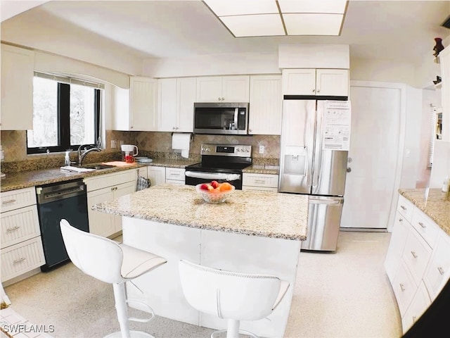 kitchen with appliances with stainless steel finishes, light stone countertops, and a kitchen breakfast bar