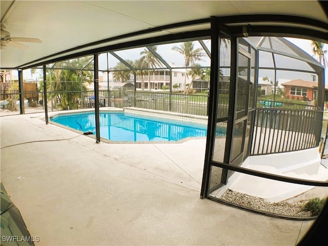 view of swimming pool with a patio, glass enclosure, and ceiling fan