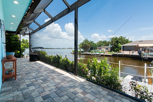 view of patio with a lanai and a water view