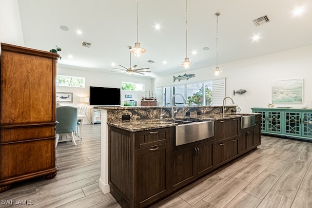 kitchen featuring sink, pendant lighting, a kitchen island with sink, and light wood-type flooring