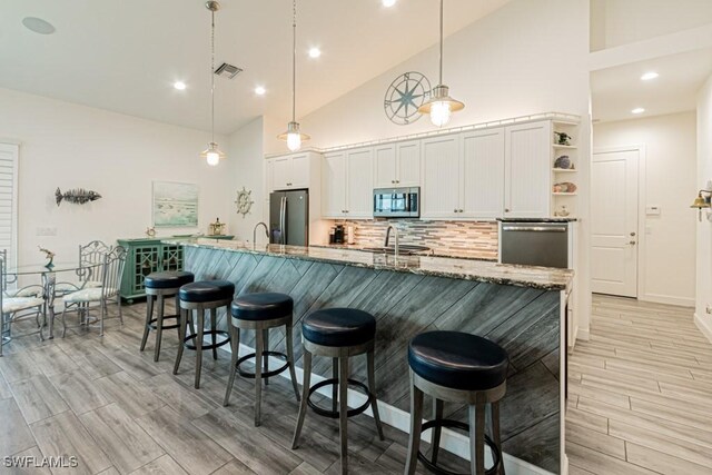 kitchen with pendant lighting, appliances with stainless steel finishes, dark stone counters, and white cabinets