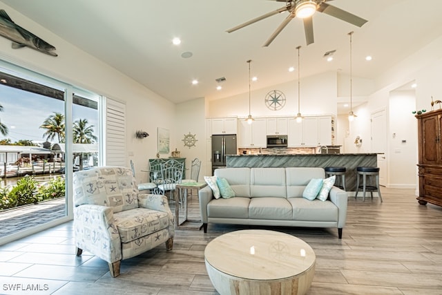 living room with high vaulted ceiling, light hardwood / wood-style floors, and ceiling fan