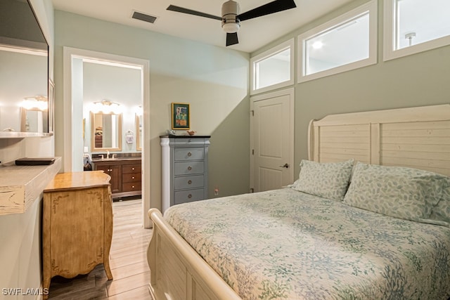 bedroom with ceiling fan, ensuite bath, sink, and light hardwood / wood-style flooring