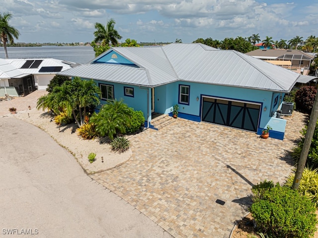 ranch-style house featuring a garage, a water view, and central air condition unit