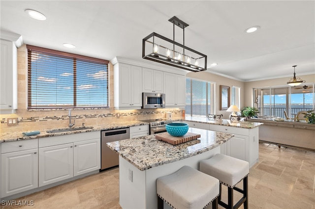 kitchen with white cabinets, a kitchen island, hanging light fixtures, and appliances with stainless steel finishes