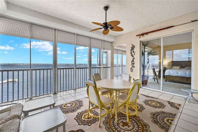 sunroom / solarium featuring a water view and ceiling fan