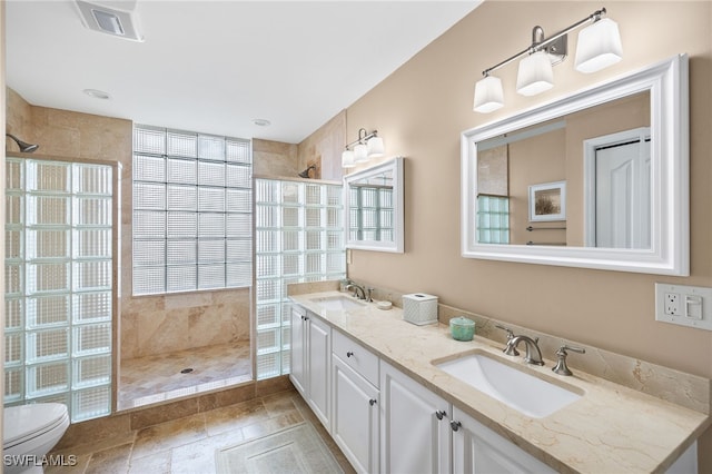 bathroom featuring vanity, toilet, and tiled shower