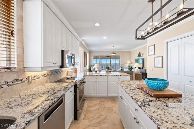 kitchen with white cabinetry, hanging light fixtures, appliances with stainless steel finishes, and ornamental molding