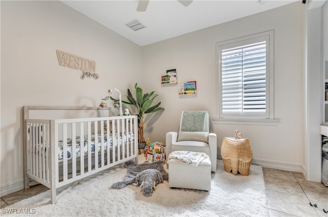 tiled bedroom featuring ceiling fan and a crib