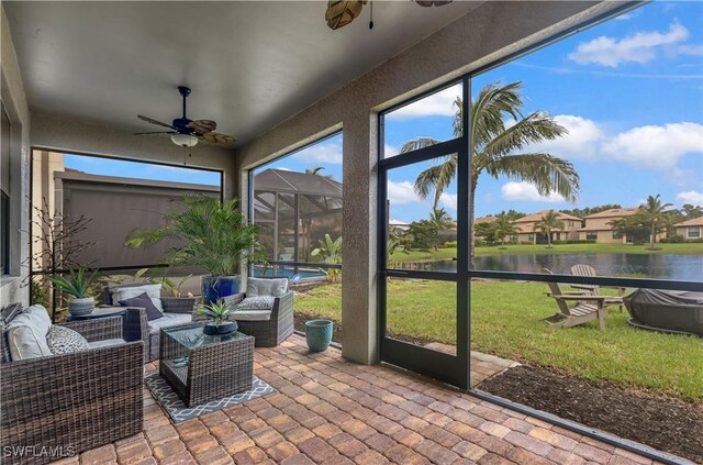 sunroom featuring ceiling fan and a water view