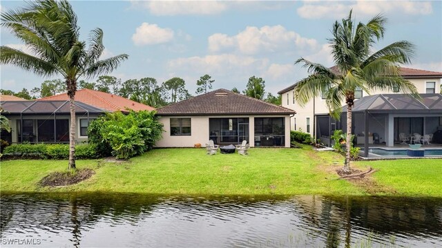 back of property featuring a lanai, a lawn, and a water view