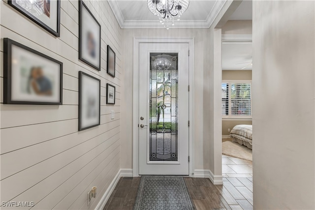 foyer with baseboards, an inviting chandelier, ornamental molding, and dark wood finished floors