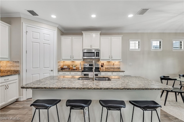 kitchen with a kitchen island with sink, a breakfast bar, plenty of natural light, and appliances with stainless steel finishes