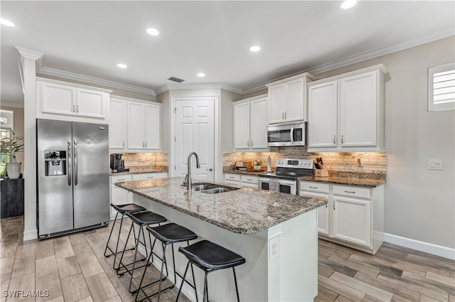 kitchen featuring a kitchen bar, white cabinets, appliances with stainless steel finishes, and a sink