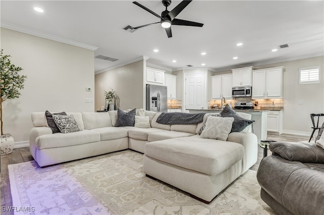 living room featuring ceiling fan, light wood-type flooring, and crown molding