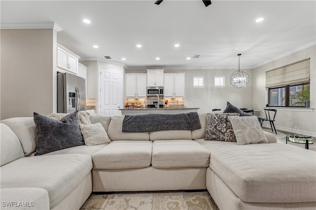 living room featuring ceiling fan with notable chandelier and crown molding