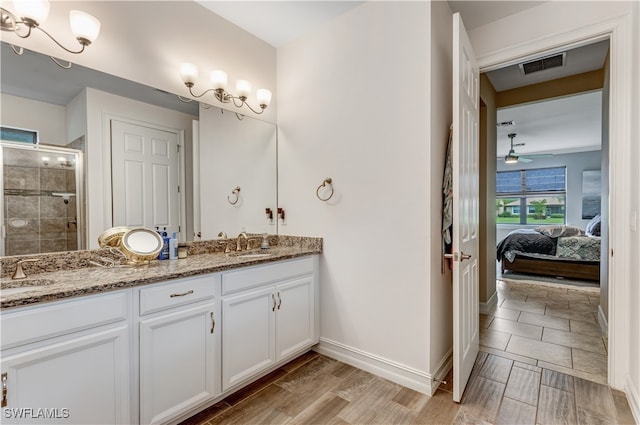 full bathroom with visible vents, connected bathroom, double vanity, a stall shower, and a sink